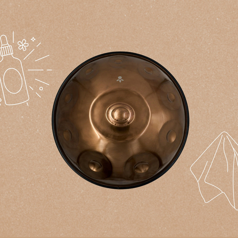 Handpan von oben auf hellem Grund, daneben gezeichnet eine Ölflasche und ein Tuch