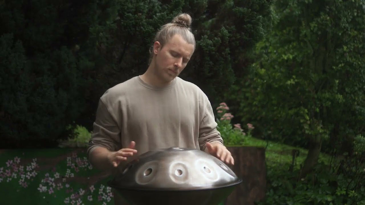 Ein Spieler sitzt im Garten und spielt Handpan