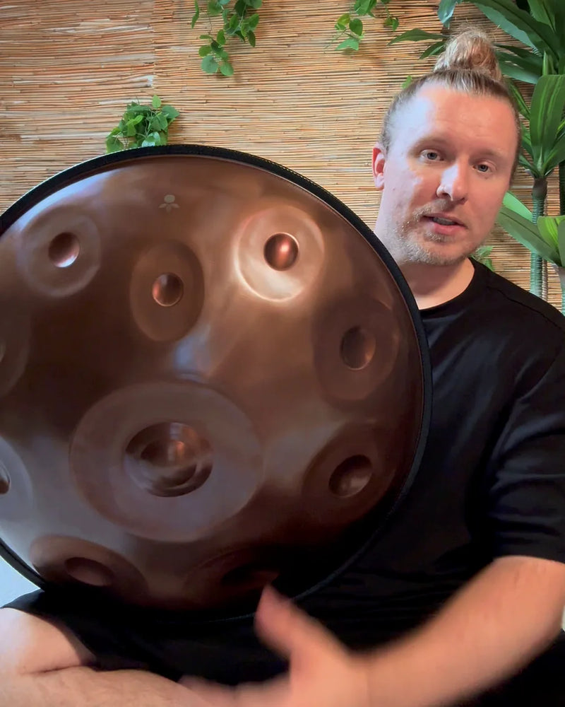 Max Neumann von handpanladen hält eine Handpan schräg vor sich und spricht in die Kamera