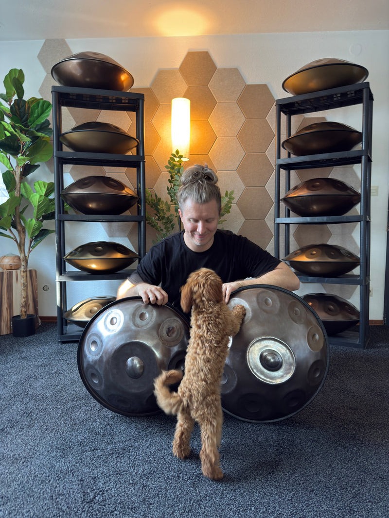 Max Neumann sitzt mit Welpe Dea zwischen zwei Handpans im Showroom von handpanladen in Balingen
