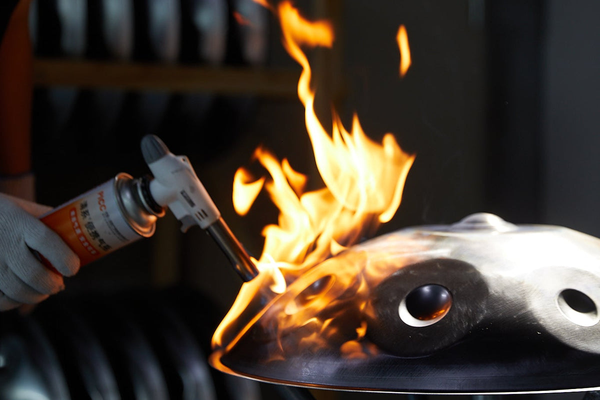 Ein Gasbrenner erhitzt eine Handpan-Schale mit offener Flamme