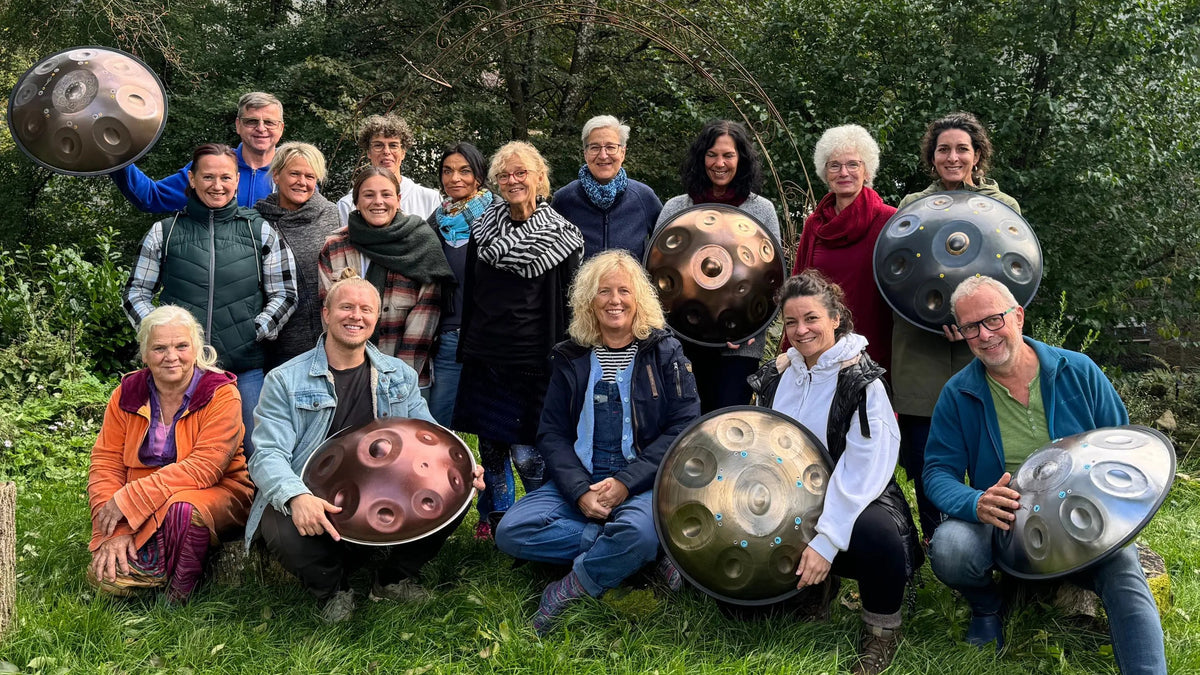 Gruppenfoto einer Workshop-Runde im Grünen, viele halten eine Handpan in den Händen