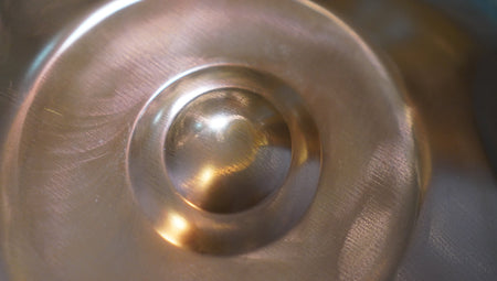 Nahaufnahme des Ding einer bronzefarbenen Handpan mit feinen Kratzern und Hammerspuren