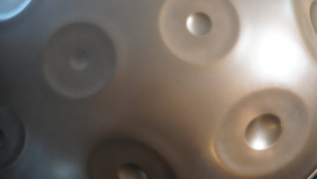 Silberne Handpan im Detail mit kleinen dunklen Flecken auf der Oberfläche