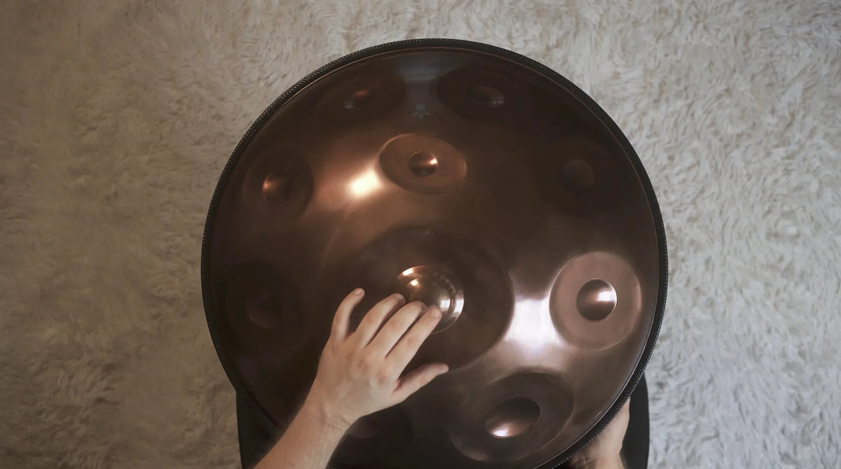 Eine Hand schlägt ein Tonfeld einer Handpan an, von oben fotografiert